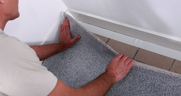 a person fitting carpet on a tiled floor