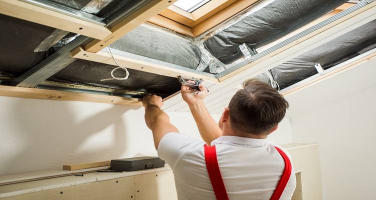 man working inside loft with velux